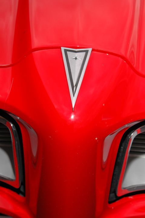 1985 Ford Crown Victoria LTD - The iconic Pontiac emblem is centered on the hood of this red vehicle.