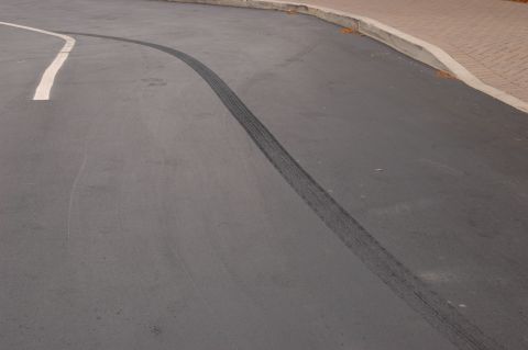 1985 Ford Crown Victoria LTD - Tire tracks mark the asphalt, indicating a vehicle's recent maneuver on the road.