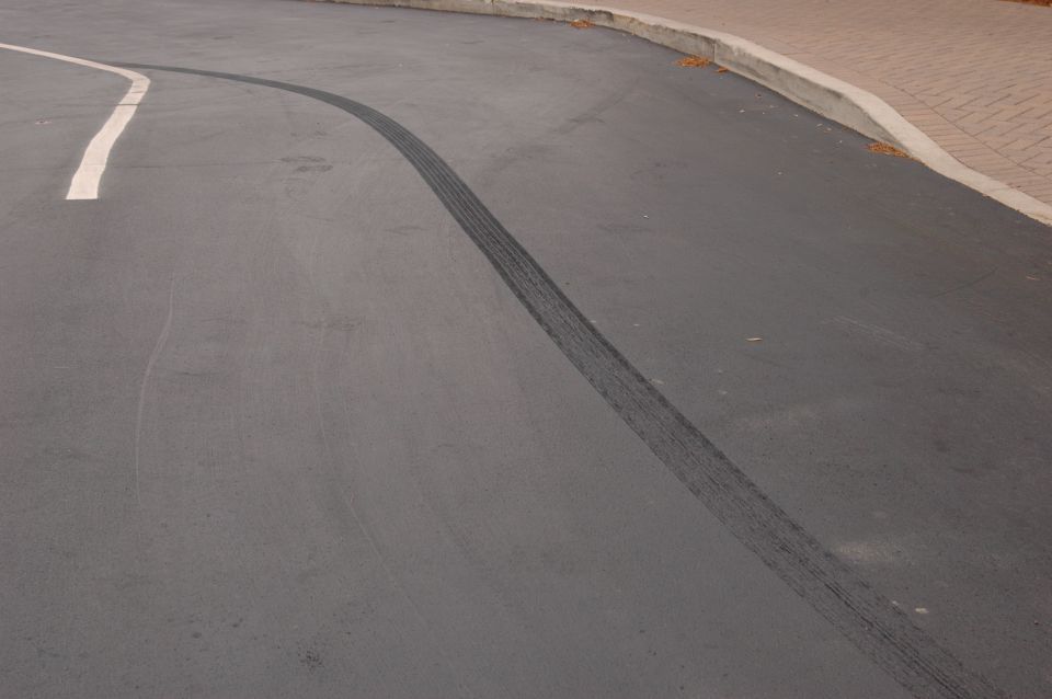 Tire tracks on asphalt road with a white line and curb