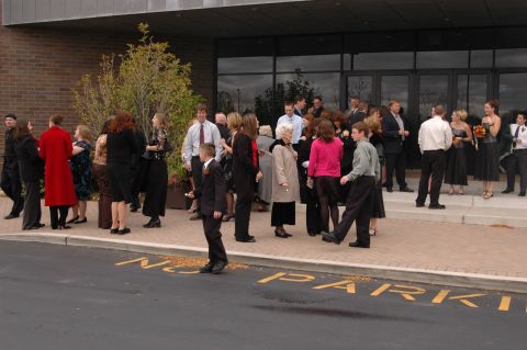 1985 Ford Crown Victoria LTD - A group of people are seen standing outside a building, possibly for an event.