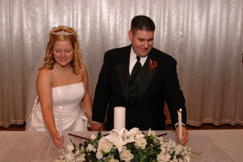 1985 Ford Crown Victoria LTD - A bride and groom hold hands while lighting candles as part of their wedding ceremony.