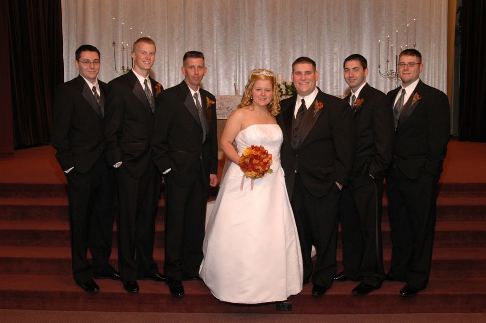 Wedding party in tuxedos and a wedding dress standing together