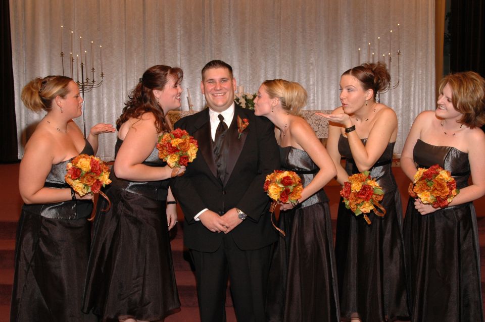 Groom with bridesmaids surrounding him, some blowing kisses
