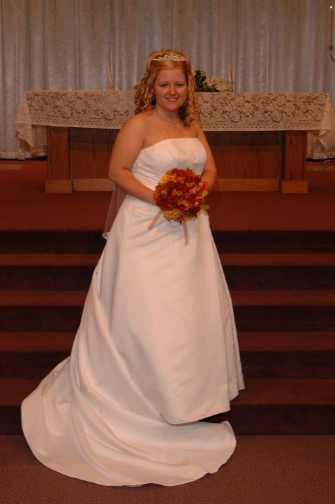 1985 Ford Crown Victoria LTD - A bride poses for a photo in a wedding dress, holding a bouquet in front of an altar.