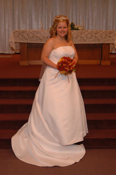 1985 Ford Crown Victoria LTD - A bride poses for a photo in her wedding dress, holding a bouquet in front of an altar.