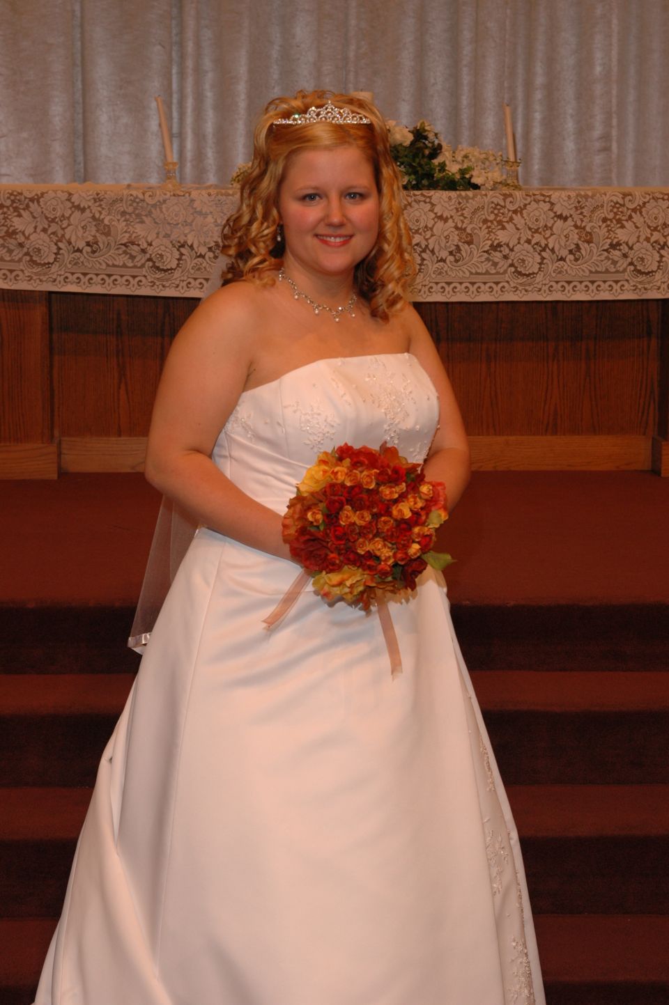 Bride in a white strapless wedding dress holding a bouquet of orange and red flowers