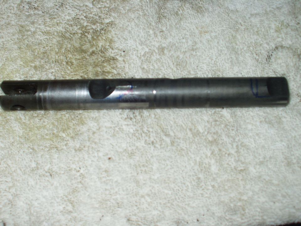 Steel shift rail shaft with slotted clevis end and milled notch lying on light carpet