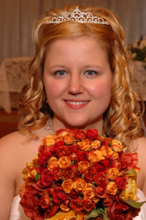 1985 Ford Crown Victoria LTD - A bride smiles while holding a bouquet of flowers, wearing a tiara.