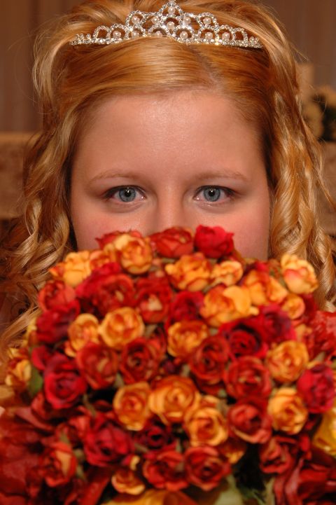 1985 Ford Crown Victoria LTD - A bride holds a bouquet of roses in front of her face, wearing a tiara.