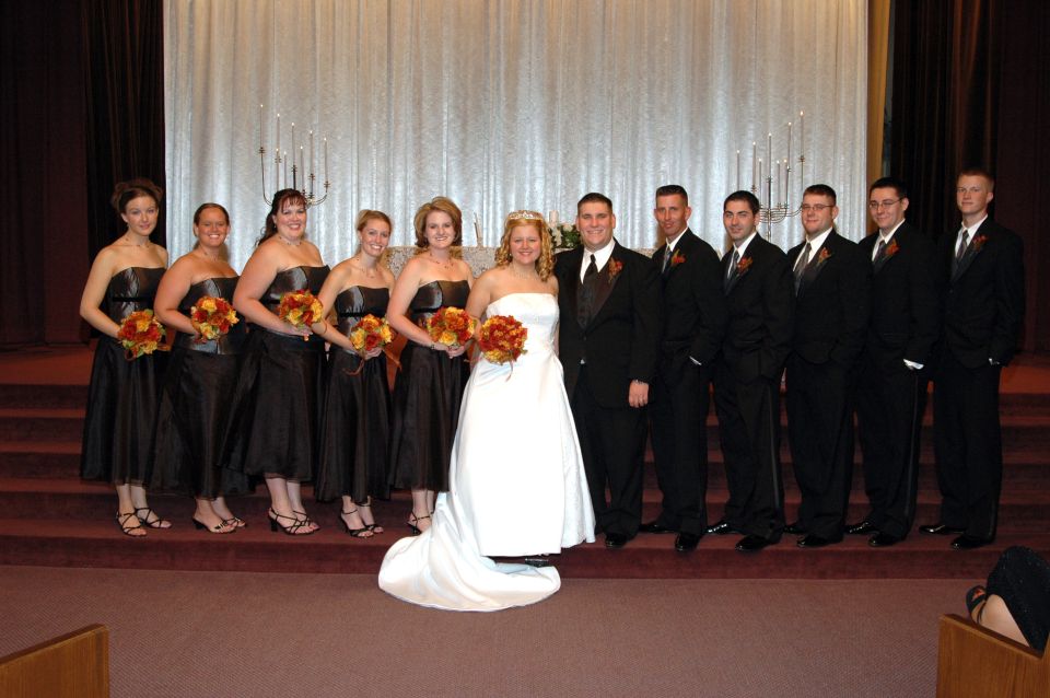 Wedding party posing for a photo in front of a white curtain backdrop