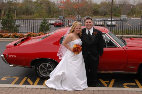 1985 Ford Crown Victoria LTD - A wedding couple poses with a classic red Pontiac GTO, a striking addition to their special day.