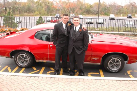 1985 Ford Crown Victoria LTD - Two men in formal wear pose next to a vintage red coupe.