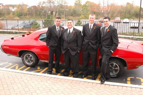 1985 Ford Crown Victoria LTD - Groomsmen pose with a vintage red car on a wedding day.
