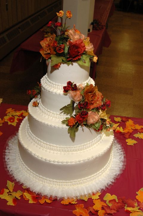1985 Ford Crown Victoria LTD - A decorative four-tier cake adorned with flowers and autumn leaves, likely for a wedding or fall celebration.