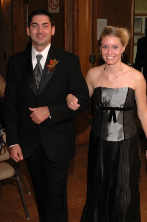 1985 Ford Crown Victoria LTD - A man in a tuxedo and a woman in a formal dress walk together, likely at a wedding event.