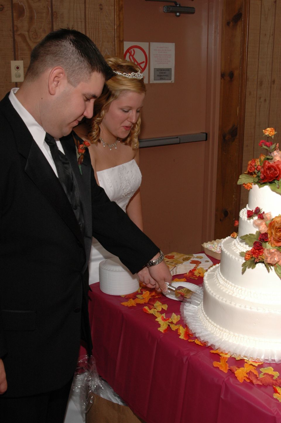 Bride and groom cutting a tiered wedding cake decorated with flowers
