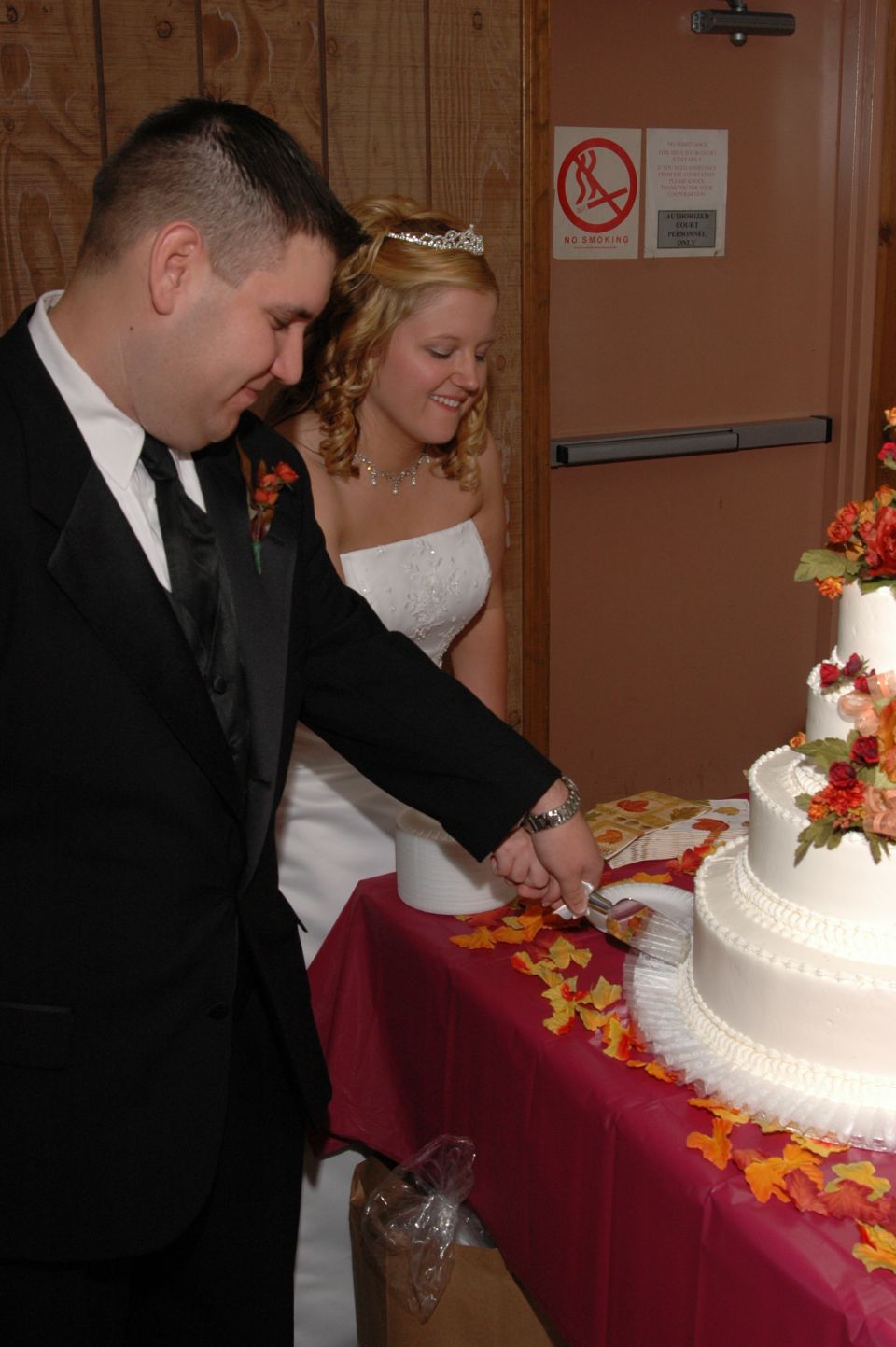 Groom and bride cutting a tiered wedding cake with floral decorations