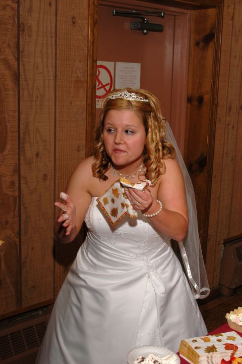 1985 Ford Crown Victoria LTD - A bride in a white wedding dress and tiara eats cake, with frosting on her hands and face.