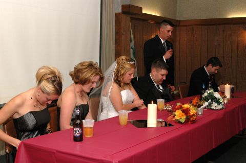 1985 Ford Crown Victoria LTD - Wedding reception guests are seated at a table with floral arrangements and candles.