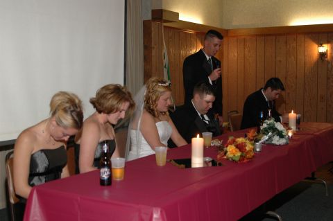 1985 Ford Crown Victoria LTD - A wedding reception scene with the wedding party seated at a table, some with heads bowed.
