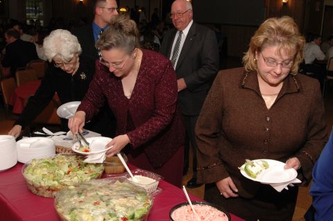 1985 Ford Crown Victoria LTD - Guests serve themselves from a buffet spread, with large bowls of salad prominently displayed.