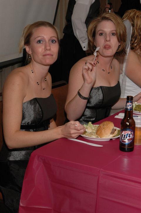 1985 Ford Crown Victoria LTD - Two women in formal dresses are seated at a table, with one woman playfully sticking out her tongue.