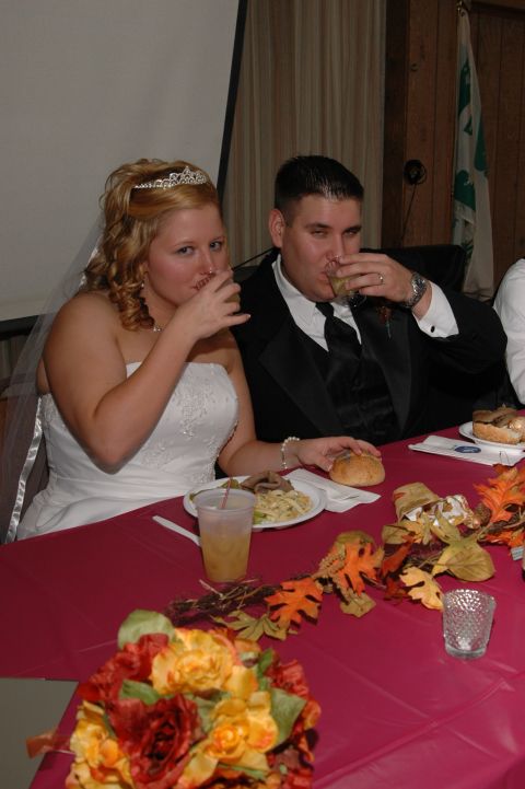 1985 Ford Crown Victoria LTD - A bride and groom toast at their wedding reception table, which is decorated with fall leaves and flowers.