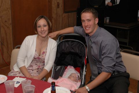 1985 Ford Crown Victoria LTD - A couple poses with their baby in a stroller at a gathering.