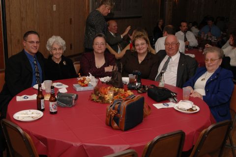 1985 Ford Crown Victoria LTD - A group of people are seated around a table at an indoor gathering, possibly a celebration.