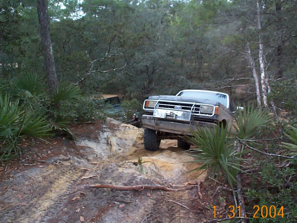 Ford Bronco on a dirt trail with another vehicle behind it in the woods