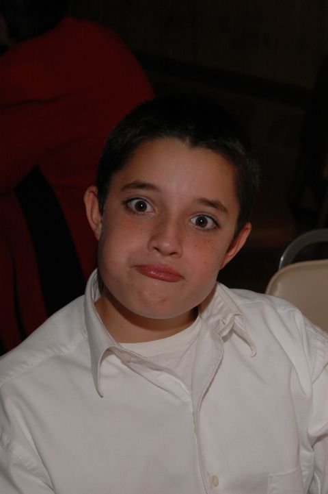 1985 Ford Crown Victoria LTD - A young boy makes a funny face with wide eyes and puffed cheeks while wearing a white shirt.