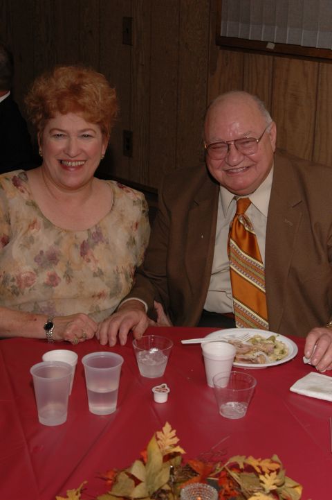 1985 Ford Crown Victoria LTD - A couple smiles while seated at a table set for a meal.
