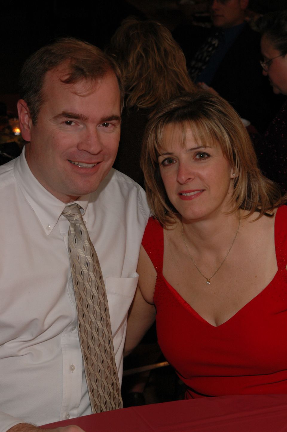 Man in white shirt and patterned tie with woman in red dress