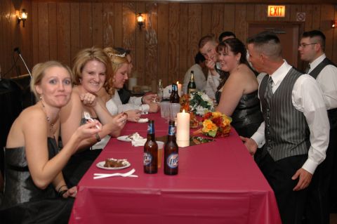 1985 Ford Crown Victoria LTD - People gathered around a table at a wedding reception, with food and drinks present.