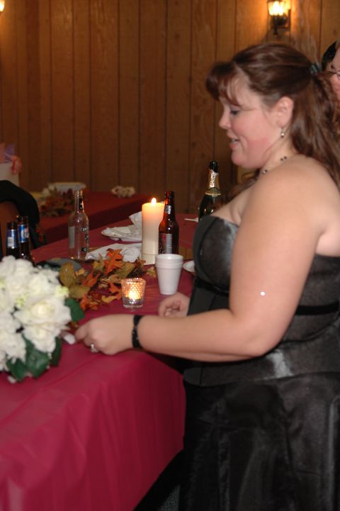 1985 Ford Crown Victoria LTD - A woman in a black dress is seated at a table decorated for an event, with flowers and drinks present.