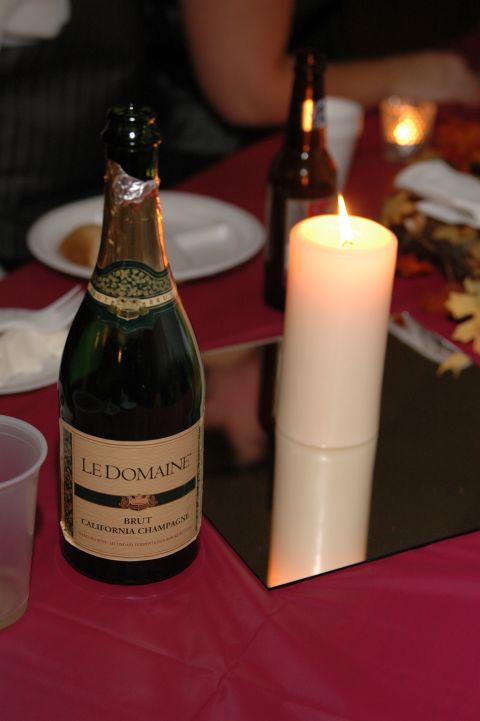 1985 Ford Crown Victoria LTD - A bottle of Le Domaine Brut California Champagne sits on a table next to a lit candle and a beer bottle.