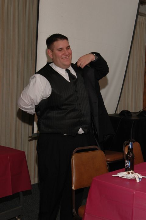 1985 Ford Crown Victoria LTD - A man dressed for a formal event adjusts his suit jacket in front of a projection screen.