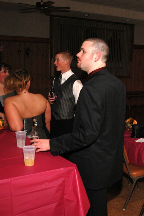 1985 Ford Crown Victoria LTD - Attendees mingle at a formal gathering, with drinks on a red-covered table.