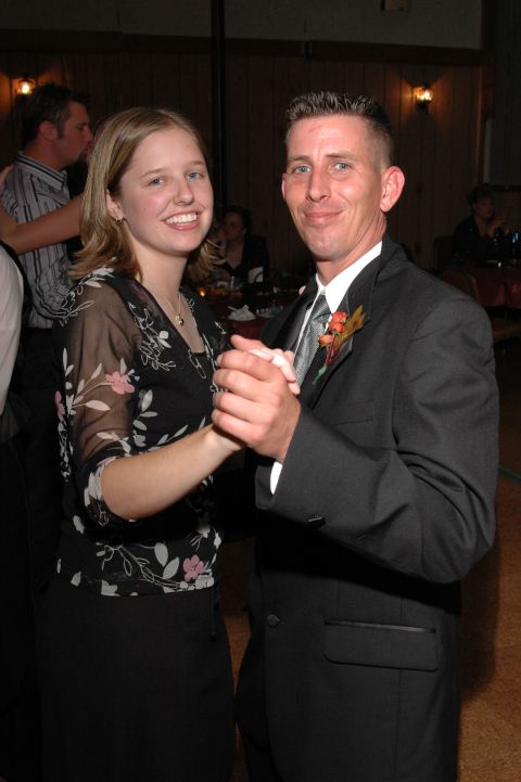 1985 Ford Crown Victoria LTD - A man in a suit and a woman in a floral dress dance together at a formal gathering.