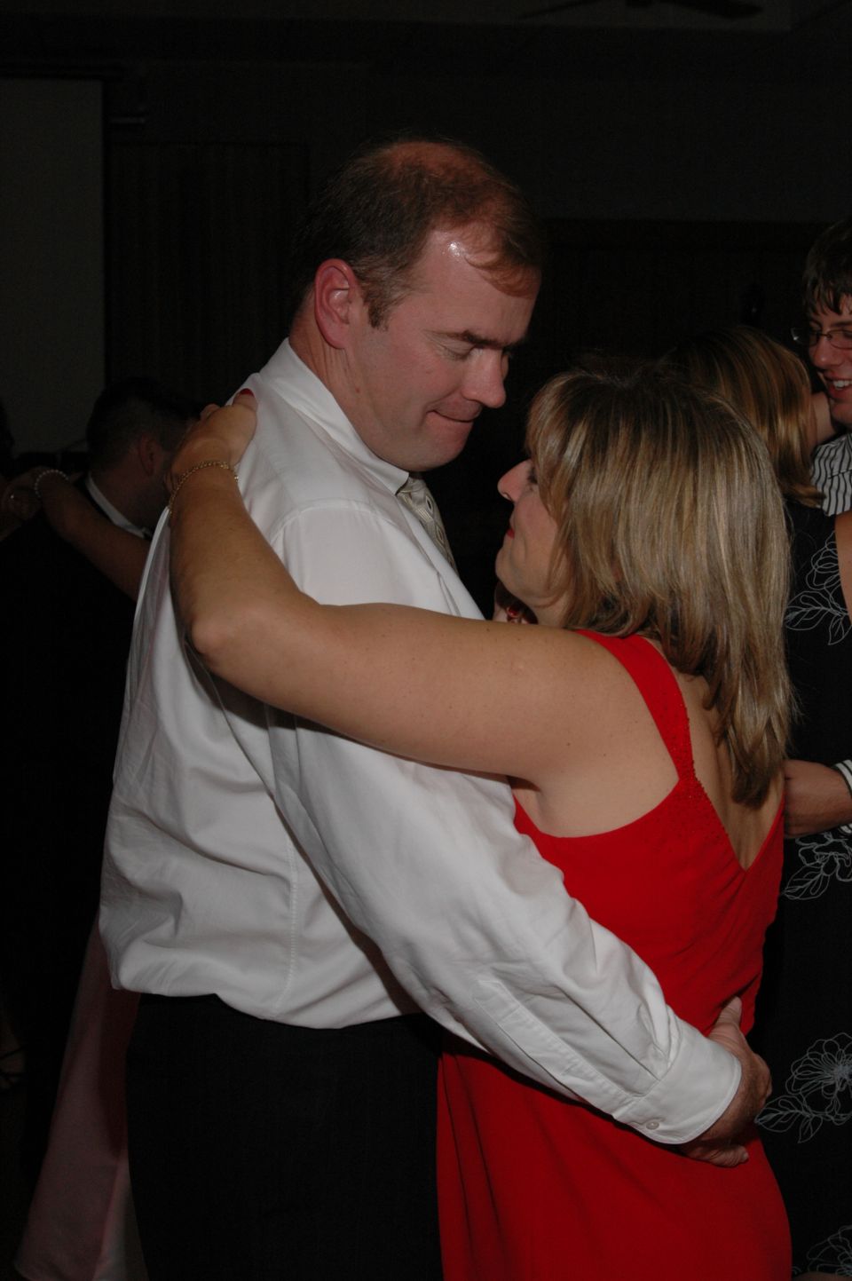 man in white shirt and woman in red dress dancing closely