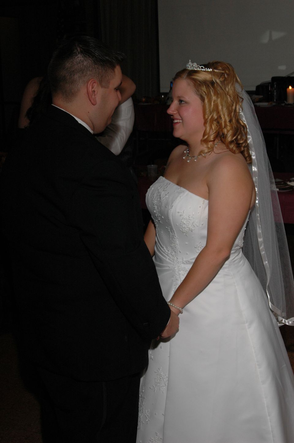 Bride in a white wedding dress and groom in a black suit hold hands