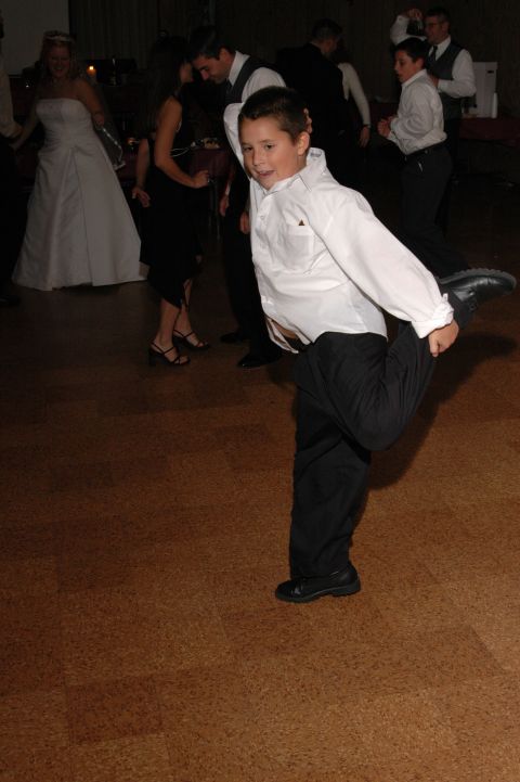 1985 Ford Crown Victoria LTD - A young boy dances energetically at a wedding reception, while guests and a bride look on.