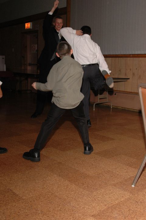 1985 Ford Crown Victoria LTD - A group of men in formal attire engage in lively dancing at an indoor event.