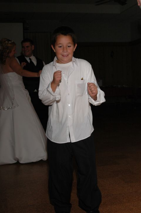 1985 Ford Crown Victoria LTD - A young boy dances enthusiastically at a wedding reception, while a bride and groom are visible in the background.