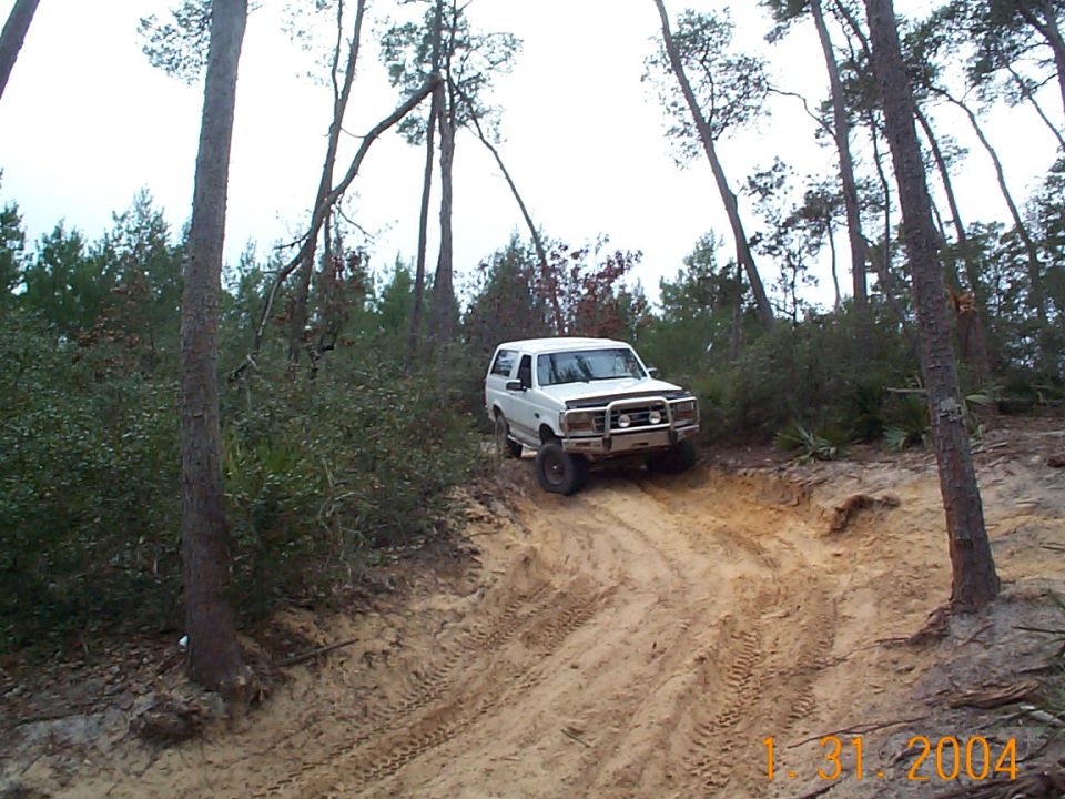 White 1992 Ford Bronco driving on a dirt trail