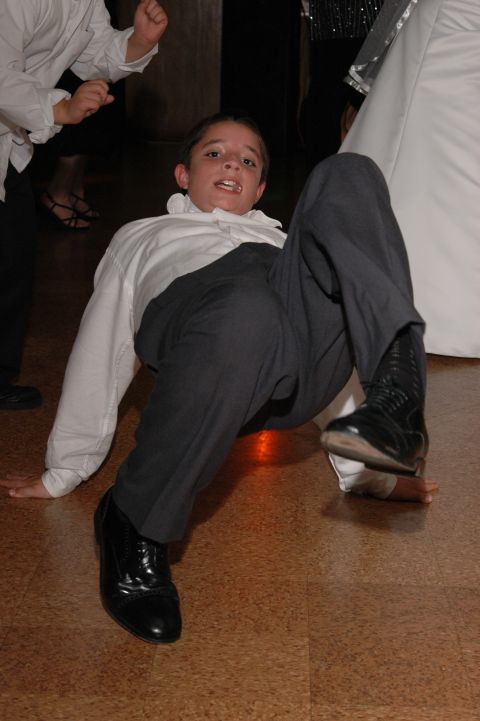 1985 Ford Crown Victoria LTD - A young boy is captured mid-dance on a wooden floor, dressed in formal attire.
