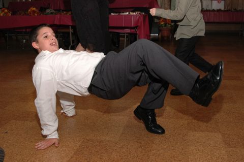 1985 Ford Crown Victoria LTD - A boy performs a dance move on the floor at an event with other people in the background.
