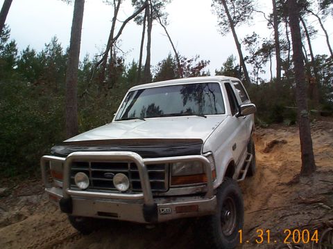 1992 Ford Bronco - White 1992 Ford Bronco navigates a wooded dirt path during an off-road excursion.