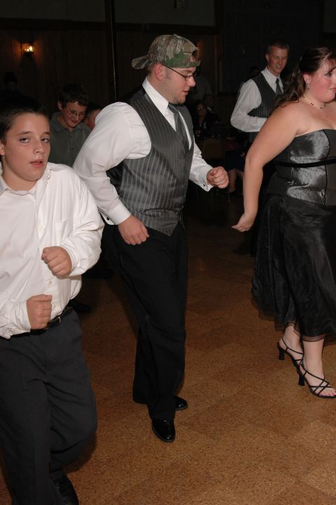 1985 Ford Crown Victoria LTD - Guests enjoy dancing at a wedding reception, with a young boy in the foreground and a couple in the background.