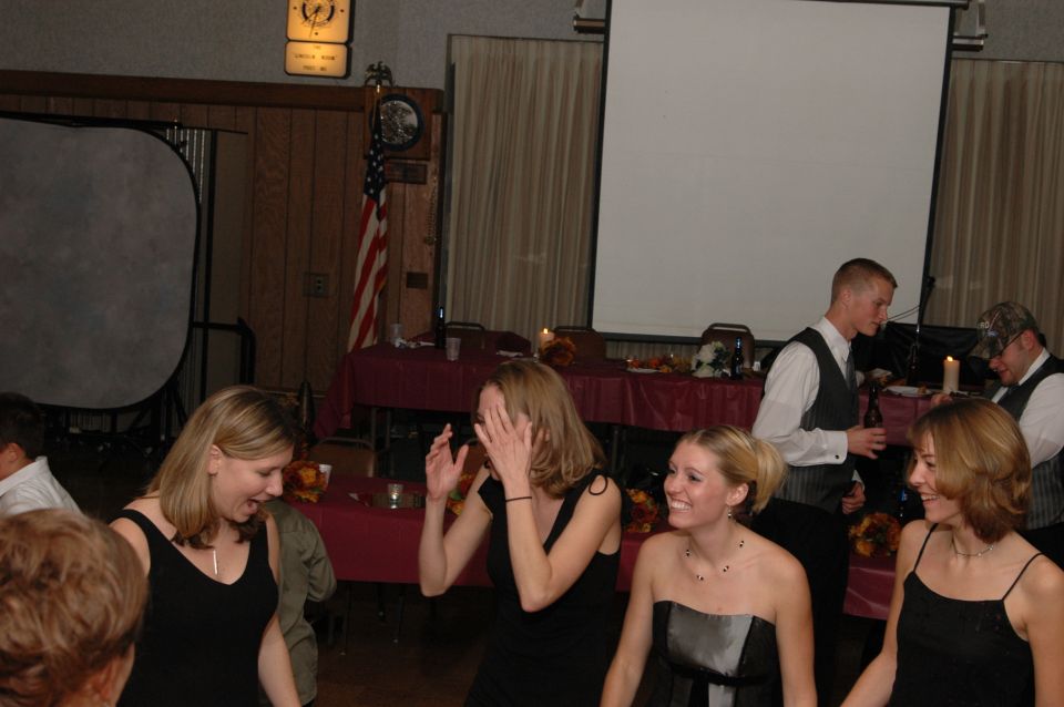 People in formal wear are gathered in a room with tables and a projector screen